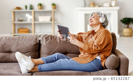 Cheerful senior woman using tablet and listening Cheerful senior woman using tablet and listening 65132287