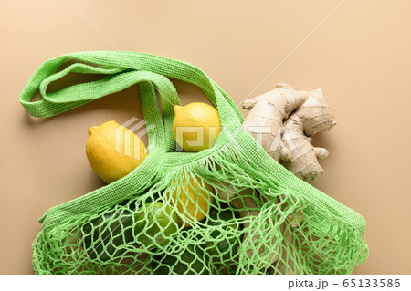 Green mesh bag with lemon and ginger on beige 65133586