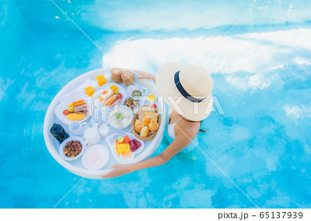 Portrait beautiful young asian woman happy smile with floating breakfast in tray on swimming pool 65137939