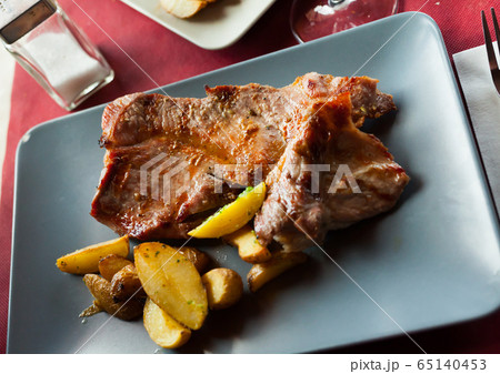 Tasty cooked fried pork with fried potatoes at plate 65140453