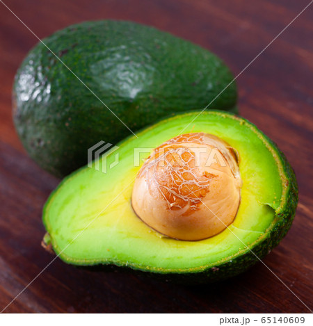 Close up of cut avocado with bone at wooden table Close up of cut avocado with bone at wooden table 65140609