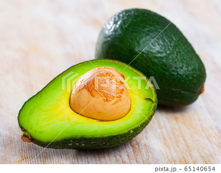 Close up of cut avocado with bone at wooden table 65140654