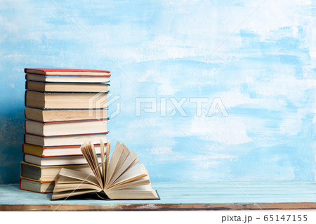 Composition with vintage old hardback books, diary, fanned pages on wooden deck table and red background. Books stacking. Back to school. Copy Space. Education background. 65147155