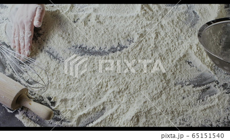 Wheat fresh flour on a wooden table and baker's hand is starting to make natural dough. Slow motion, Full HD video, 240fps, 1080p. Step by step dough pie preparation. Top view. 65151540