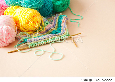 Colored yarn for knitting, knitting needles and scissors. Female hobby concept. Beige background. 65152222
