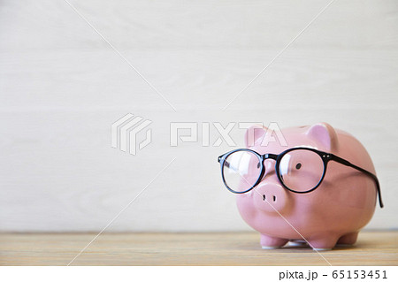Piggy bank with glasses on the wooden background 65153451