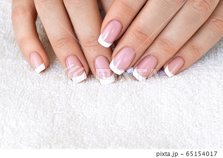 Female fingers with beautiful French manicure on white terry towel, close up, selective focus. 65154017