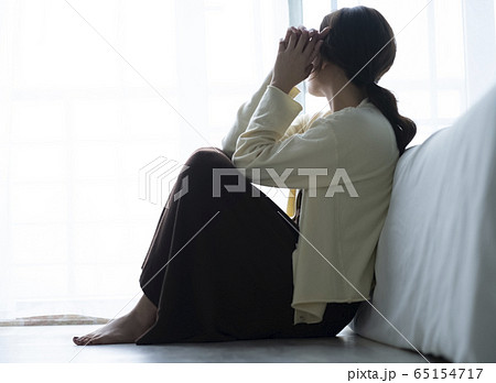 床に座って落ち込む女性の写真素材