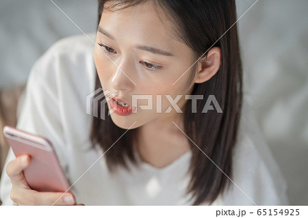 ベッドに寝転ぶ若い女性 65154925