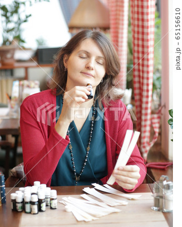 young woman in cafe with tea set smells perfumes with blotter close up photo 65156610