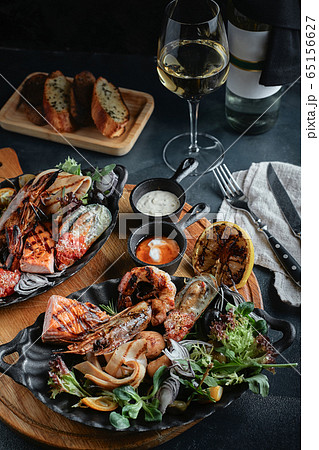 Assorted seafood on a large plate with a bottle of wine, table setting for dinner. Traditional Italian food. Seafood Wine Concept. Assorted seafood on a large plate with a bottle of wine, table setting for dinner. Traditional Italian food. Seafood Wine Concept. 65156627