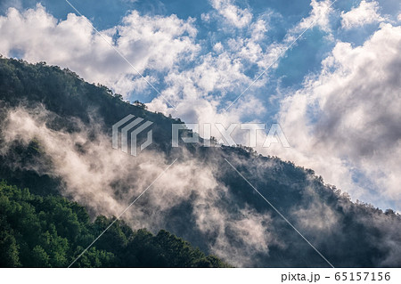 High mountains with green slopes and rocks hidden in thick clouds and fog High mountains with green slopes and rocks hidden in thick clouds and fog 65157156
