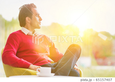 Young thoughtful businessman sitting while Young thoughtful businessman sitting while 65157407
