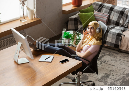 A pretty young muslim woman at home during quarantine and self-insulation, remote working, shopping, studying, watching cinema 65160543