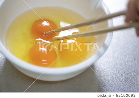 箸を使ってなま卵３つを調理する料理イメージ 65160695