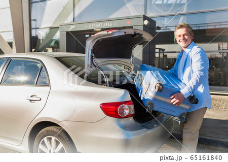 Portrait of mature businessman putting his luggage Portrait of mature businessman putting his luggage 65161840