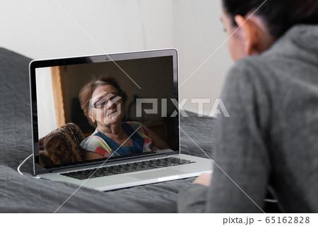 Young woman talking with elderly woman by video call at home. Remote medicine, nurse, tech 65162828