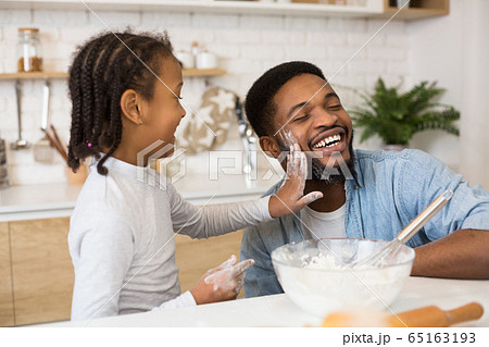 Cheerful father and daughter having fun while cooking 65163193