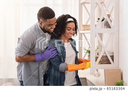Loving Black Couple Cleaning Flat Together, Wiping Dust From Shelves Loving Black Couple Cleaning Flat Together, Wiping Dust From Shelves 65163304