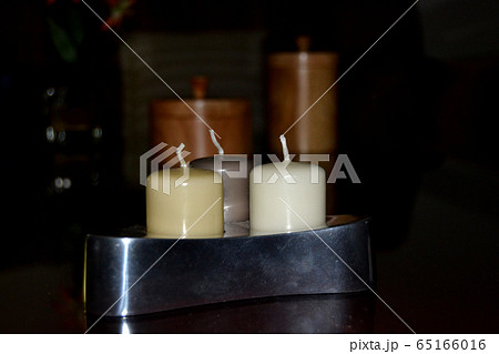 Silver candleholder containing three coloured candles in brown tones 65166016