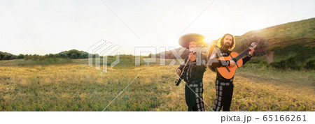 Mexican musicians mariachi on the background of field and mountains at sunset. Mexican musicians mariachi on the background of field and mountains at sunset. 65166261