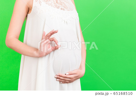 Close up of happy pregnant woman in white dress 65168510