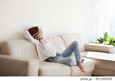 Happy woman relaxing on comfortable sofa enjoying weekend at hom 65169009