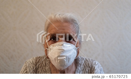 Slow motion portrait of senior woman puts on a protective respirator. 65170725