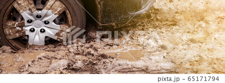 The car got stuck on a dirt road in the mud. Wheel of a car stuck in the mud on the road. Car on a 65171794
