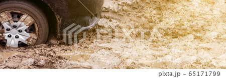 The car got stuck on a dirt road in the mud. Wheel of a car stuck in the mud on the road. Car on a 65171799