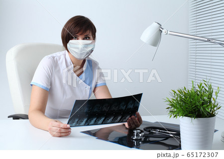 Doctor in protective mask holding MRI scan 65172307