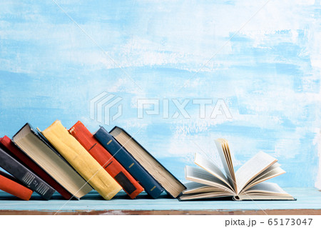 Composition with vintage old hardback books, diary, fanned pages on wooden deck table and abstract background. Books stacking. Back to school. Copy Space. Education background. Composition with vintage old hardback books, diary, fanned pages on wooden deck table and abstract background. Books stacking. Back to school. Copy Space. Education background. 65173047