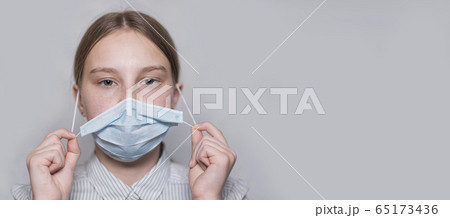 teenager girl 12-15 years old, removes medical mask, end of virus, disease gone, recovery and freedom, child recovered, free space for copy text. Flu infection disease and pandemic. Gray background. teenager girl 12-15 years old, removes medical mask, end of virus, disease gone, recovery and freedom, child recovered, free space for copy text. Flu infection disease and pandemic. Gray background. 65173436