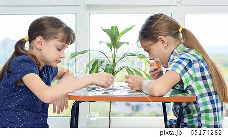 Children at home at the table collect puzzle 65174282