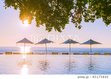 Beautiful tropical outdoor beach sea ocean with umbrella and chiar around outdoor swimming pool at sunset or sunrise time 65175830