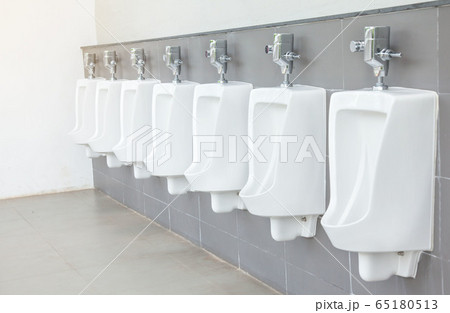 Men's room with white porcelain urinals in line. 65180513