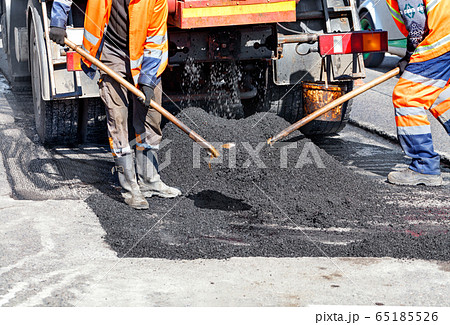 A team of road workers patches part of the road A team of road workers patches part of the road 65185526