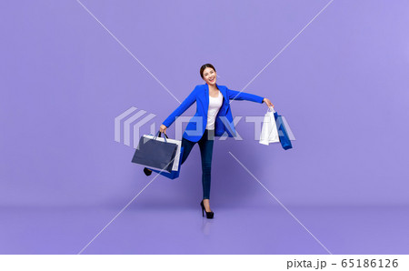 Smiling beautiful young Asian woman holding shopping bags 65186126