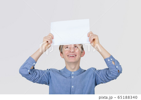 Smiling teenager boy holding a white paper above 65188340