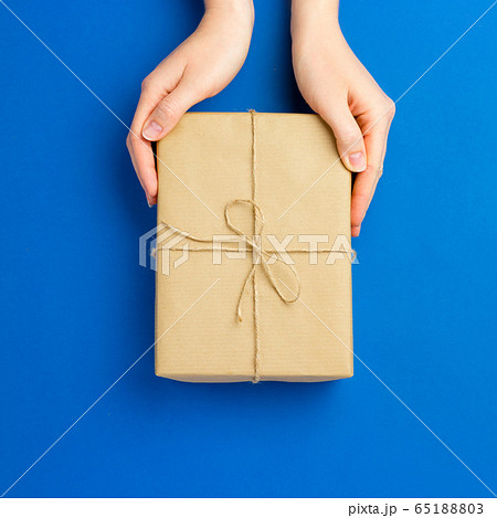 Top view of female hands holding present box package on Blue background. Zero waste shopping concept. Flat lay banner, top view, Sustainable lifestyle. Composition for birthday, mother day or xmas 65188803