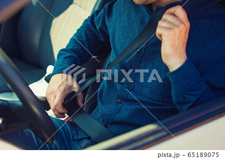 Close up man driver fastening seat belt. Guy 65189075