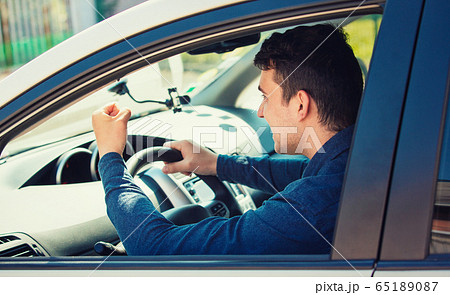 Young man driver yelling and shaking his fist Young man driver yelling and shaking his fist 65189087