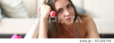 Girl does exercises with dumbbells on carpet. 65189748