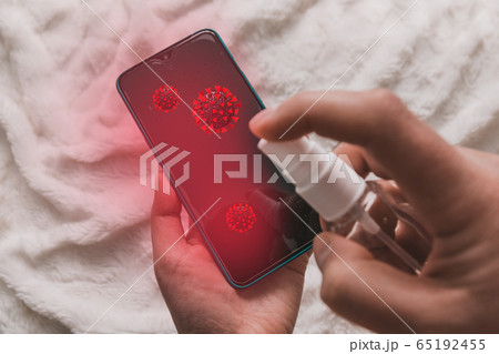 Human hand puffs an antibacterial agent on a smartphone device to protect against viruses and mocrobes Human hand puffs an antibacterial agent on a smartphone device to protect against viruses and mocrobes 65192455