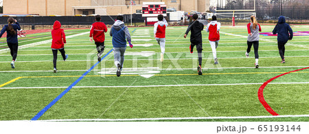 Track runners doing warm up running drills on turf 65193144