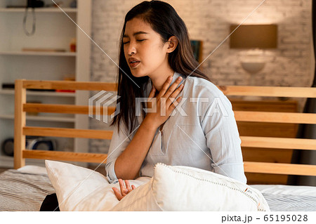 Portrait of 20s young Asian woman suffering pain and medical sickness in bedroom at night. Sore Throat, neck related pain symptoms Portrait of 20s young Asian woman suffering pain and medical sickness in bedroom at night. Sore Throat, neck related pain symptoms 65195028