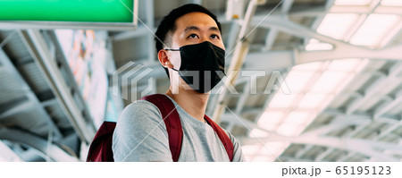 Close up of one young Asian man wearing a black surgical face mask waiting for the train during new type Coronavirus Covid-19 pneumonia outbreak and pm 2.5 smog air pollution crisis in big city 65195123