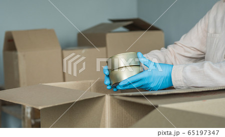 Volunteer packs canned goods in a cardboard box, prepares food kits Volunteer packs canned goods in a cardboard box, prepares food kits 65197347