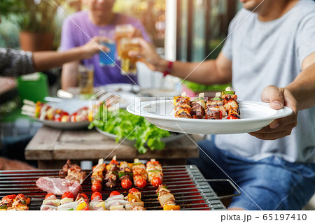 A man with a barbecue plate at a party between friends. A man with a barbecue plate at a party between friends. 65197410