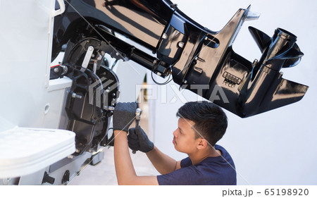Mechanic is installing speed boat engine 65198920